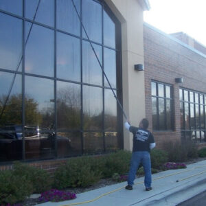 Photo of Powerhouse Pete cleaning commercial storefront windows using an extended pole