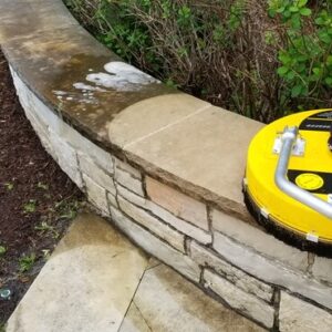 Photo of concrete pavers being hot washed with plants in background