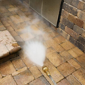 Photo of brick pavers being power washed beside an outdoor kitchen
